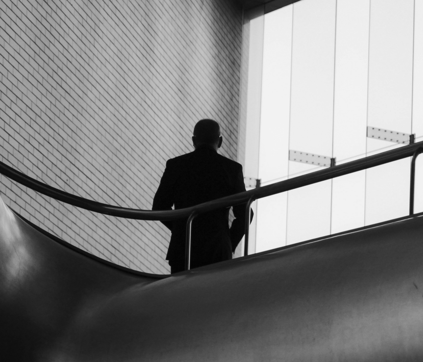 A figure descending a curved staircase in a modern building.